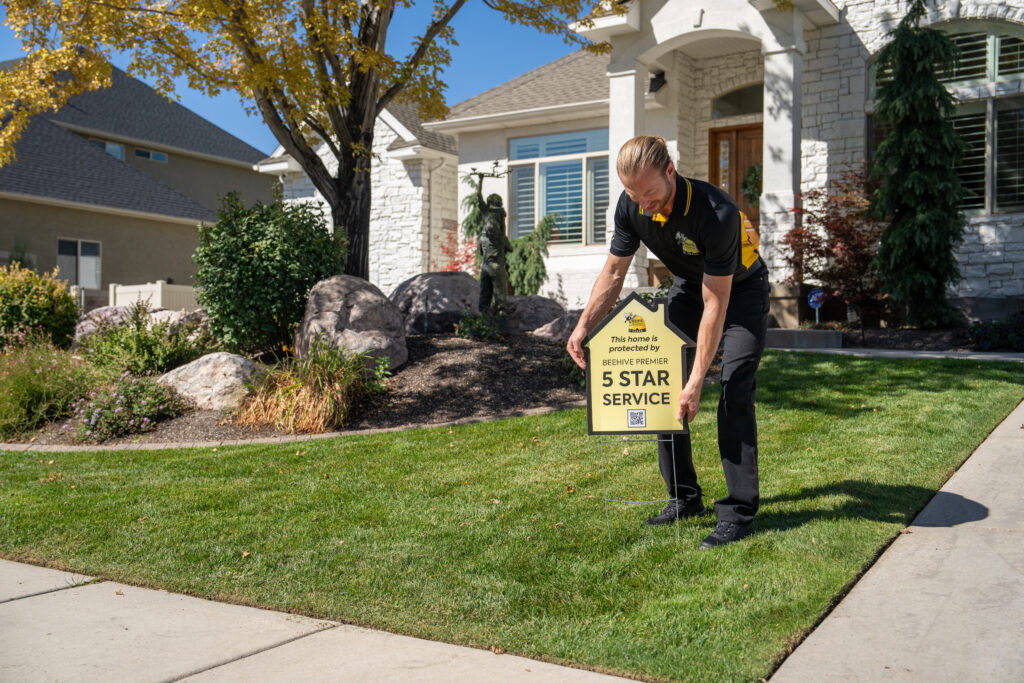 plumber in uniform placing yard sign in front of house